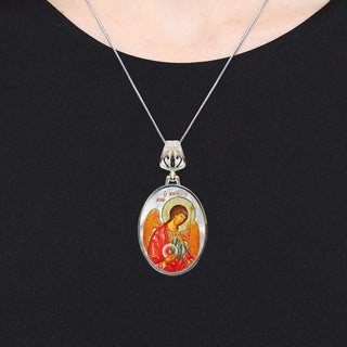 A silver necklace with a pendant featuring an image of a religious figure, such as a saint or angel.