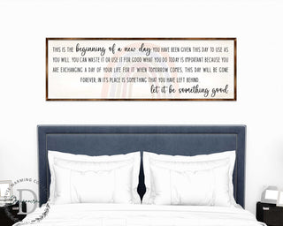 a bedroom setting with a bed and a framed inspirational quote on the wall above it.