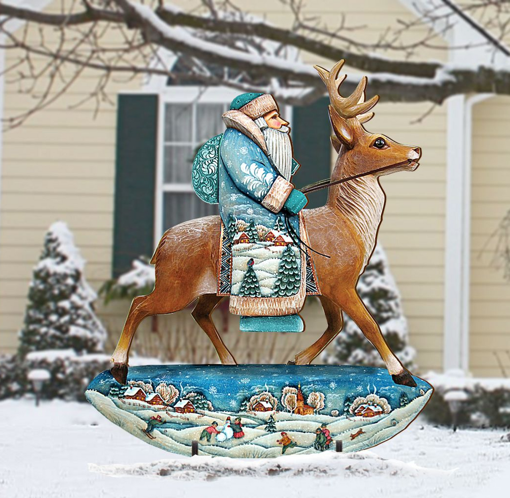 A wooden sculpture of Santa Claus riding a reindeer in a snowy landscape, with a house and trees in the background.