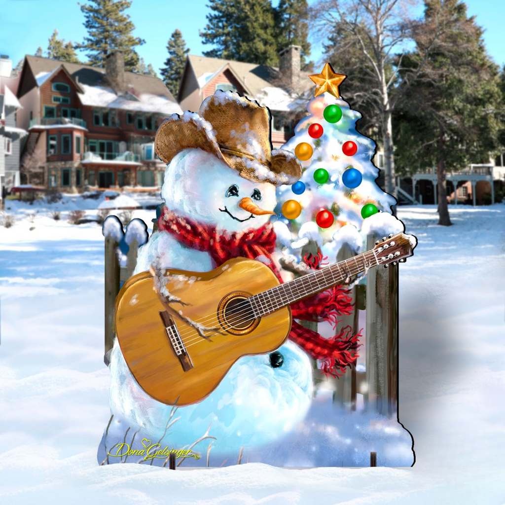 A snowman wearing a cowboy hat and scarf is holding a guitar, with a Christmas tree and houses in the background.