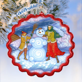 A decorative ornament featuring a snowman and two people, with a wreath and a ribbon, against a snowy background.