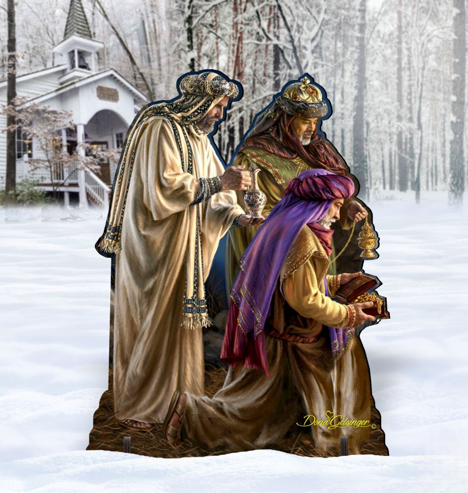 A cardboard cutout of three figures in traditional robes, likely representing the Three Wise Men, is shown in a snowy outdoor setting.
