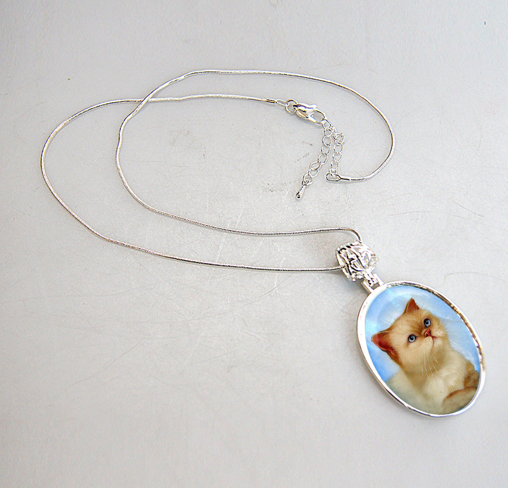 A silver necklace with a pendant featuring a picture of a cat.
