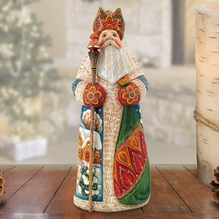 A colorful ceramic figurine of a saint or religious figure, wearing a traditional outfit with intricate patterns and designs, stands on a wooden surface.