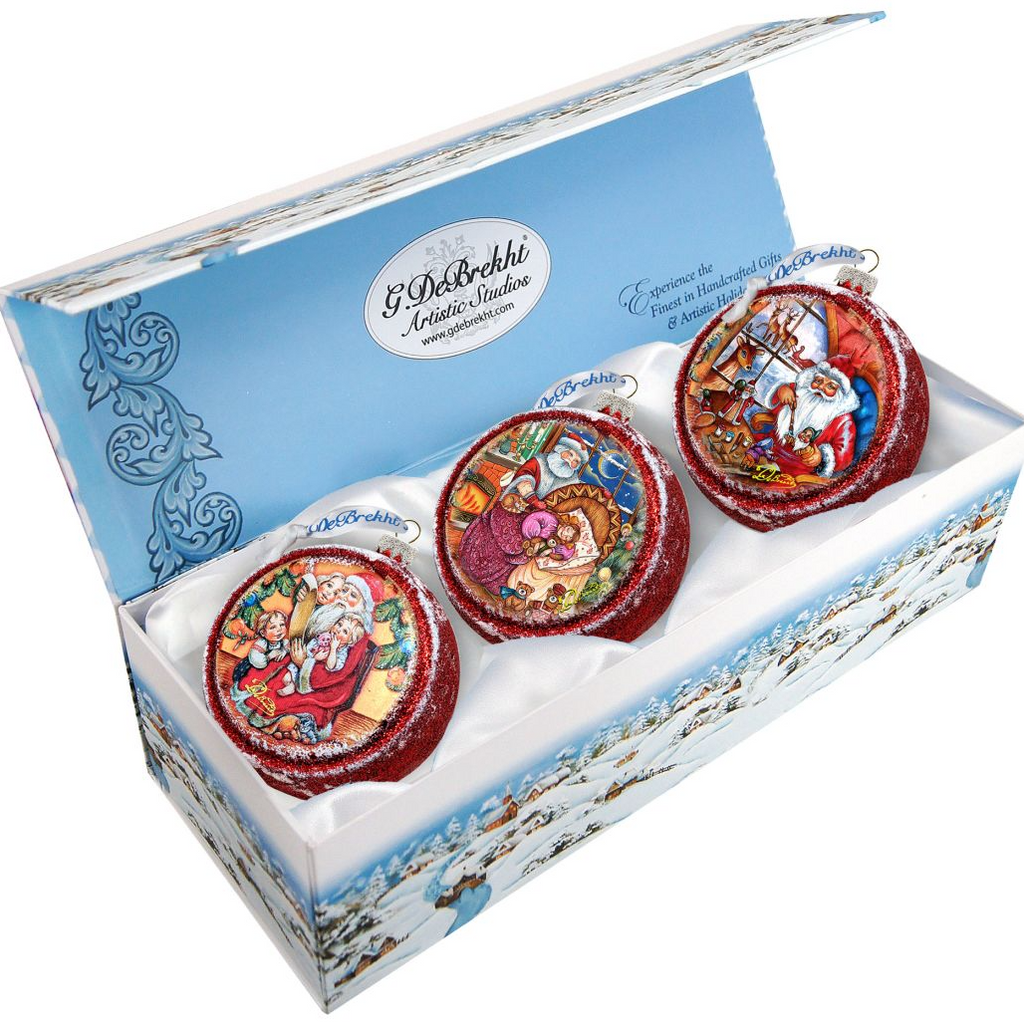 A set of three decorative Christmas ornaments in a box, each with a unique design.