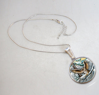 A silver necklace with a round pendant featuring an owl design.