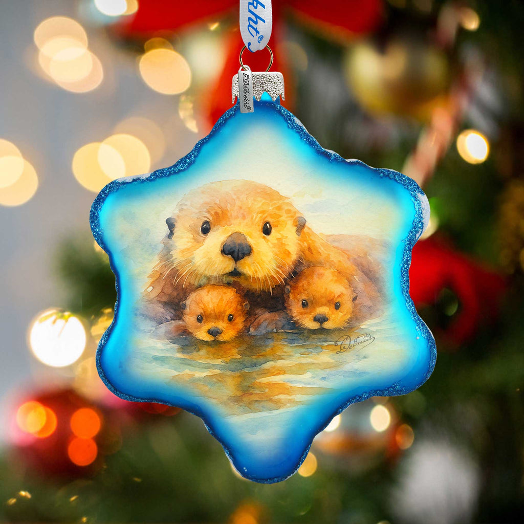 A blue star-shaped ornament with a painting of a mother otter and her two cubs.