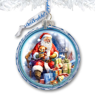 a glass ornament with a santa clause holding a teddy bear