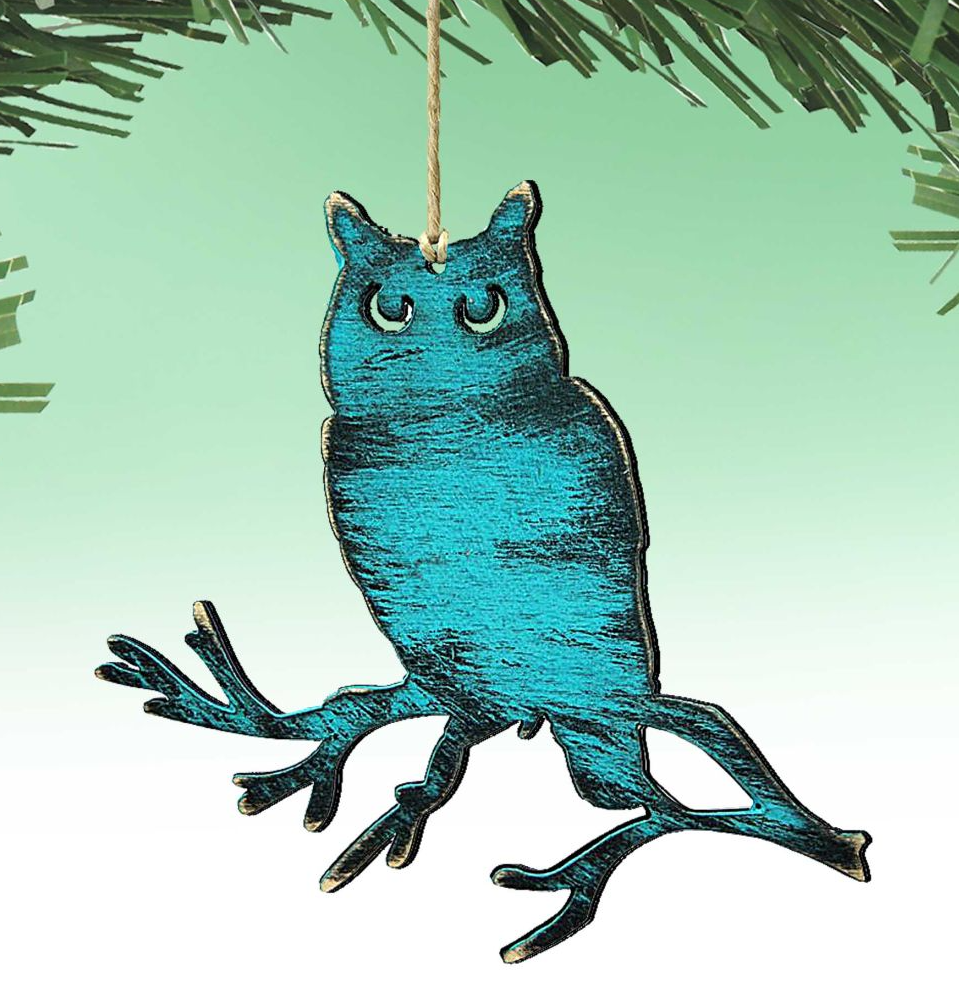 A blue owl ornament is hanging from a string against a green background.