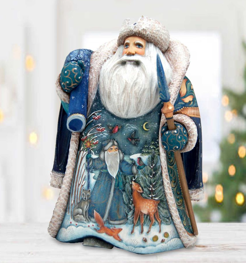 A figurine of Santa Claus holding a blue scarf and a blue staff, with a snowy landscape and animals in the background.