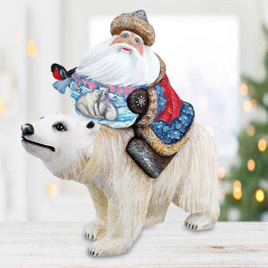 A figurine of Santa Claus riding on top of a polar bear, with a bird perched on Santa's shoulder.
