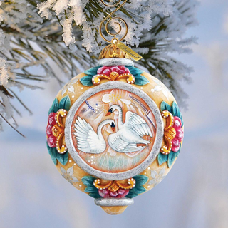 A decorative Christmas ornament featuring a pair of swans, with a floral design and a gold-colored finial.
