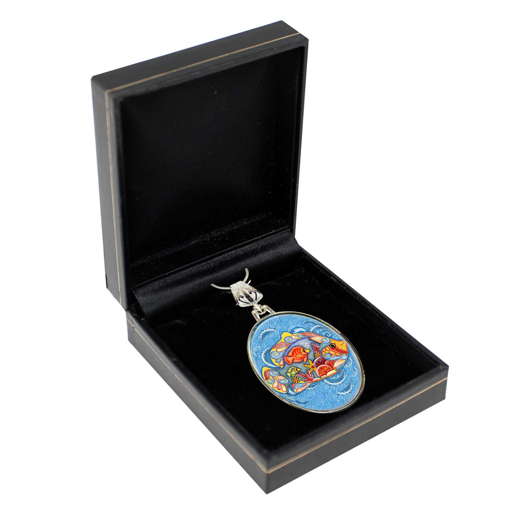 A black jewelry box containing a decorative pendant with a colorful, abstract design.