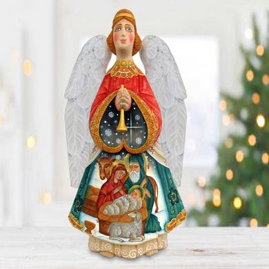 A wooden figurine of an angel holding a trumpet, with a nativity scene depicted inside the angel's body.