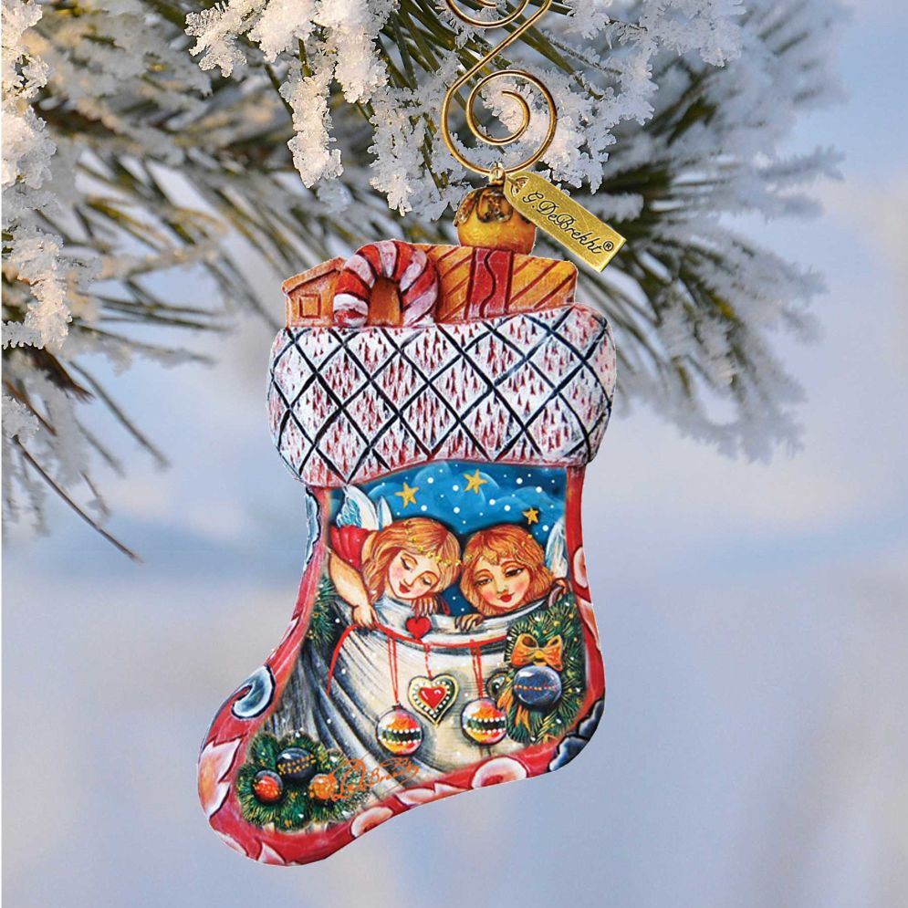 A colorful Christmas ornament in the shape of a stocking, hanging from a tree branch covered in snow.