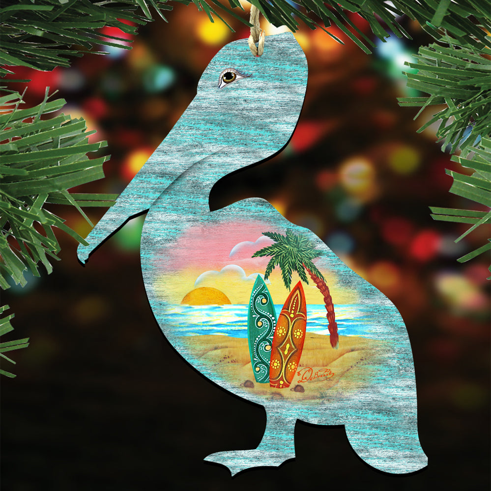 A wooden ornament in the shape of a pelican, with a palm tree and surfboards painted on it, is hanging on a branch with green leaves.
