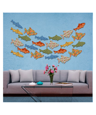 a modern living room with a gray sofa, a glass coffee table, and a wall adorned with colorful fish-shaped wall art. The fish are arranged in a visually appealing pattern, creating a lively and vibrant atmosphere in the room.