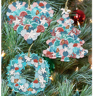 a Christmas tree decorated with three ornaments. The ornaments are shaped like hearts, trees, and wreaths, all adorned with seashells and other marine elements.