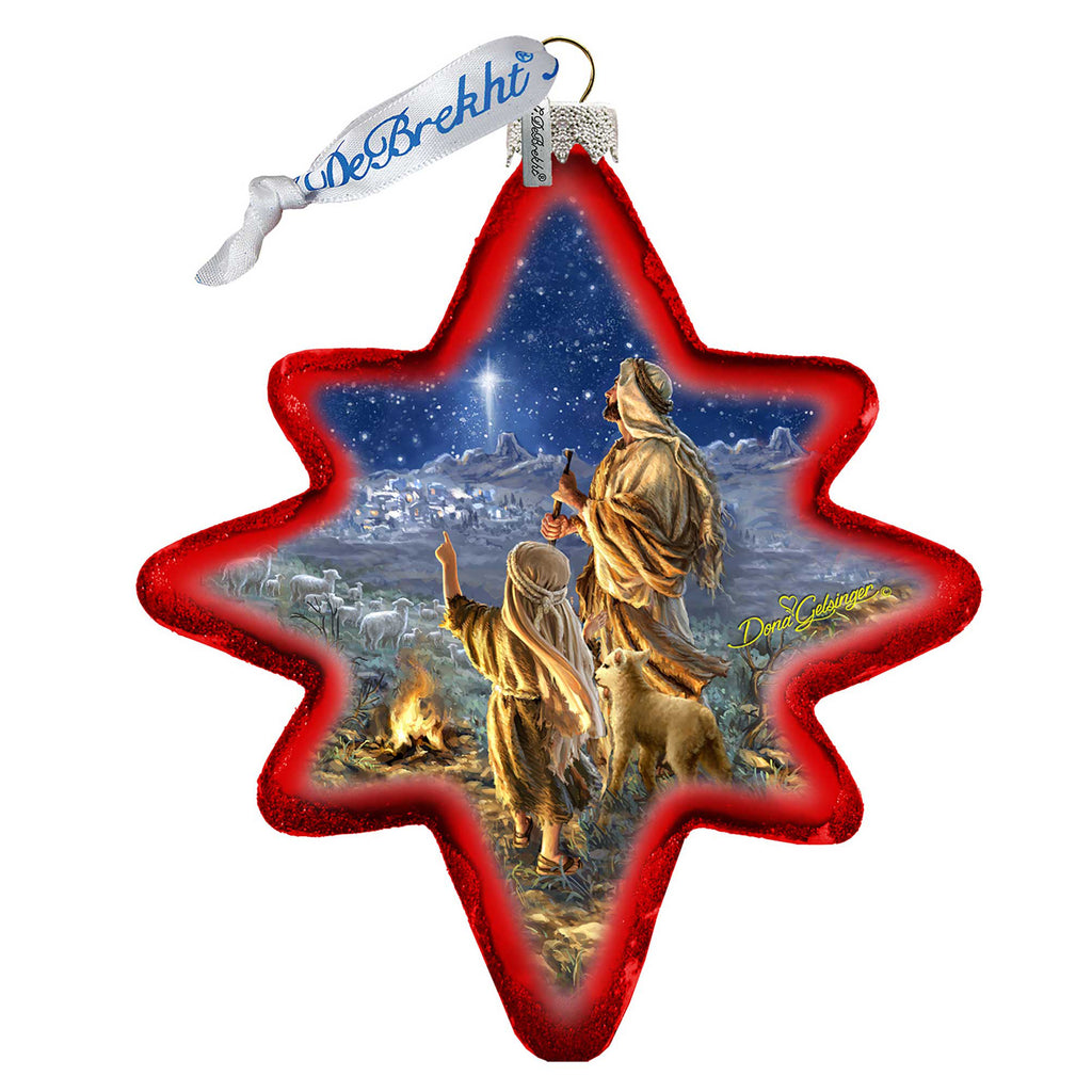A star-shaped ornament with a scene depicting two people, likely a mother and child, standing in a field with a dog. The background shows a night sky with stars and a bright light, possibly a shooting star.