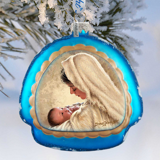 A blue ornament with a picture of a woman holding a baby, hanging against a snowy background.