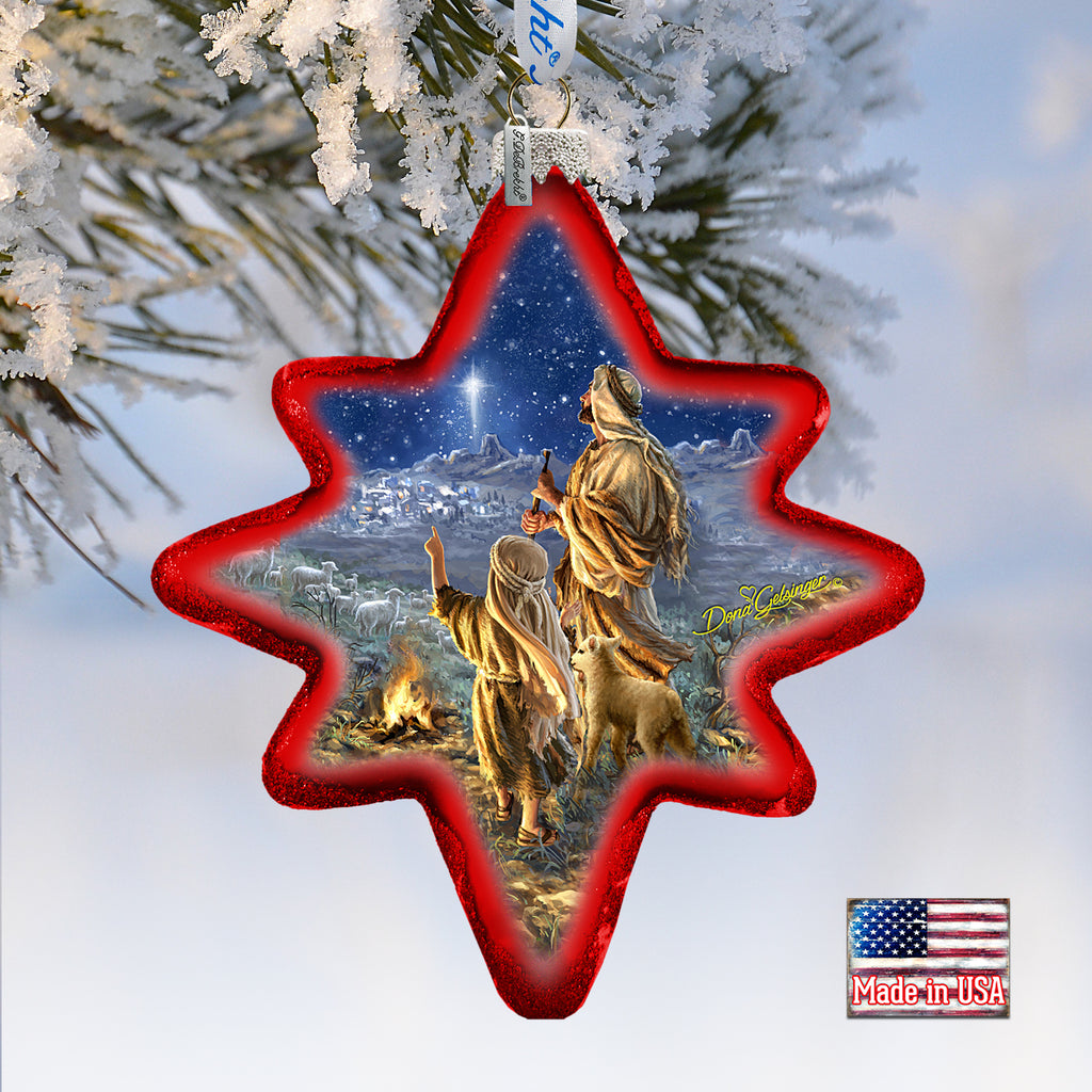 A Christmas ornament shaped like a star, with a scene of a man and a child looking up at the night sky, surrounded by snow and mountains.
