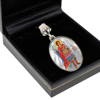 A pendant with a religious icon is displayed in a black jewelry box.