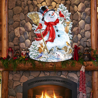 A snowman decoration with a red scarf, a broom, and various bird figurines is displayed above a fireplace, surrounded by holiday decorations and greenery.