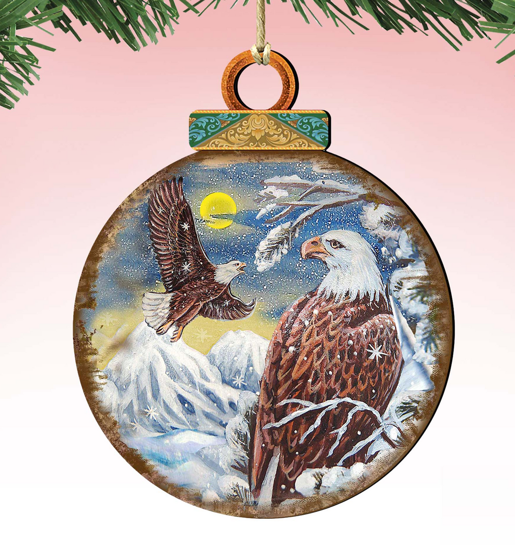 A wooden ornament depicting two bald eagles against a snowy mountain landscape with a full moon.