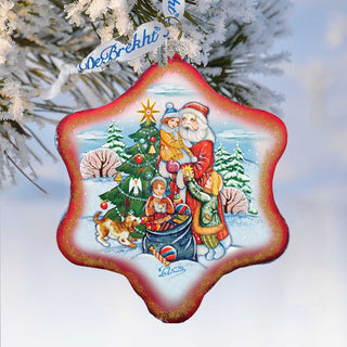 A red star-shaped ornament with a Christmas tree and Santa Claus figures, along with other holiday-themed elements, hangs from a tree branch.