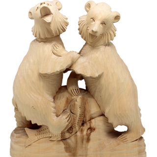 A wooden carving of two bears, one on each side, with fish in their mouths, against a black background.