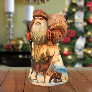 A wooden Santa Claus figurine with a detailed design of a deer, bear, and pine tree, standing on a wooden surface.