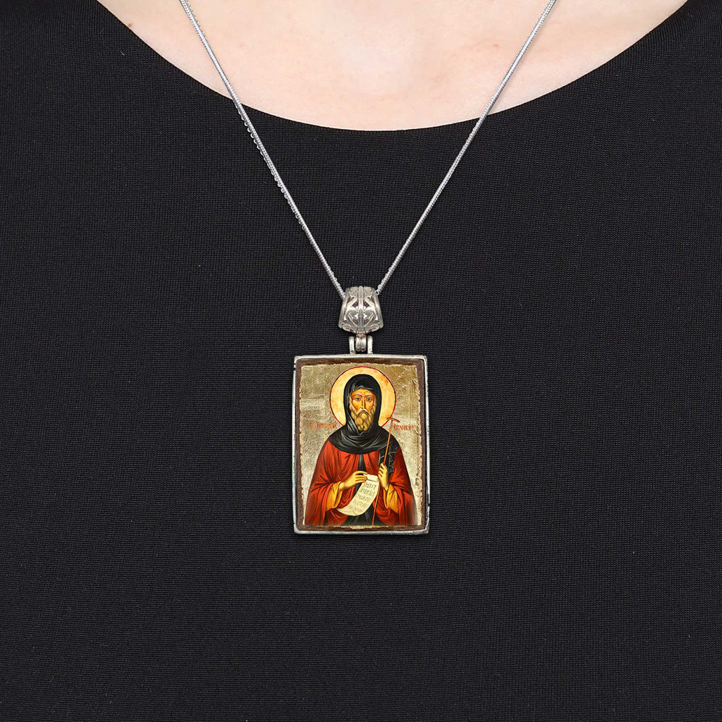 A silver necklace with a rectangular pendant featuring a religious icon.