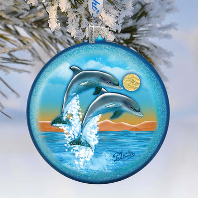 A blue ornament with a painting of two dolphins leaping out of the water, set against a snowy background.