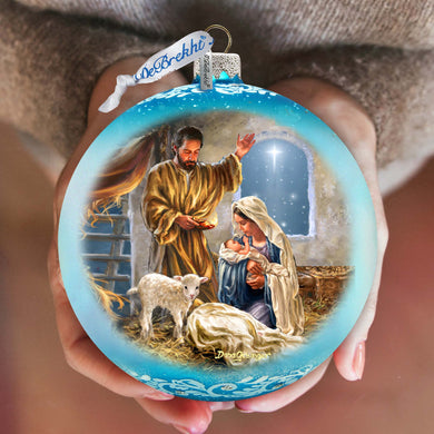 a person holding a christmas ornament with a nativity scene on it