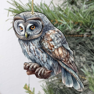 an owl ornament hanging from a pine tree