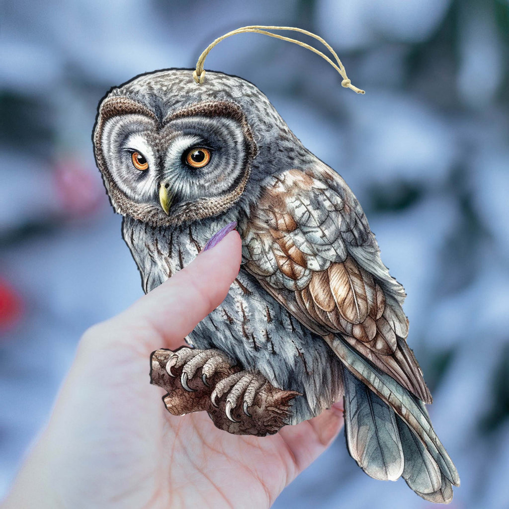 a hand holding a small owl figurine on a branch