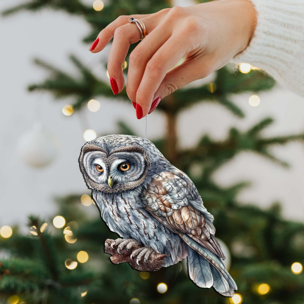 a hand holding an owl ornament on a christmas tree