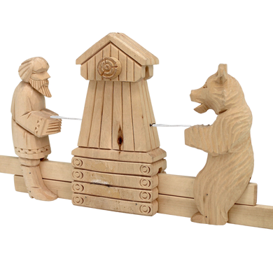 A wooden sculpture depicting a man playing a musical instrument and a bear standing next to a wooden structure.
