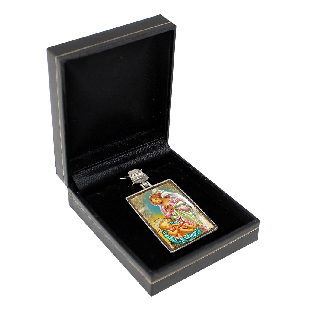 a pendant with a religious scene, displayed in a black jewelry box.