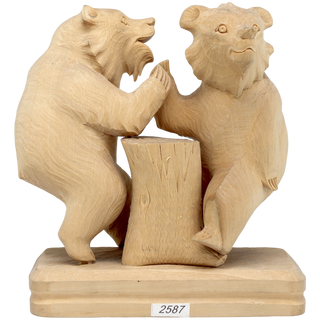 A wooden sculpture depicting two bears standing on a tree stump.
