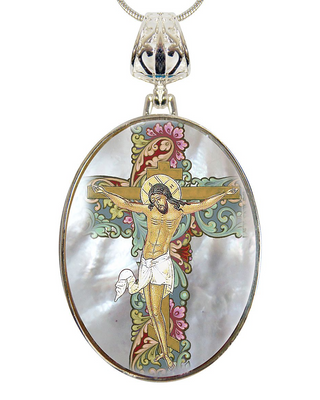 A pendant featuring a religious scene of Jesus Christ crucified, with intricate floral and ornamental designs surrounding the central figure.