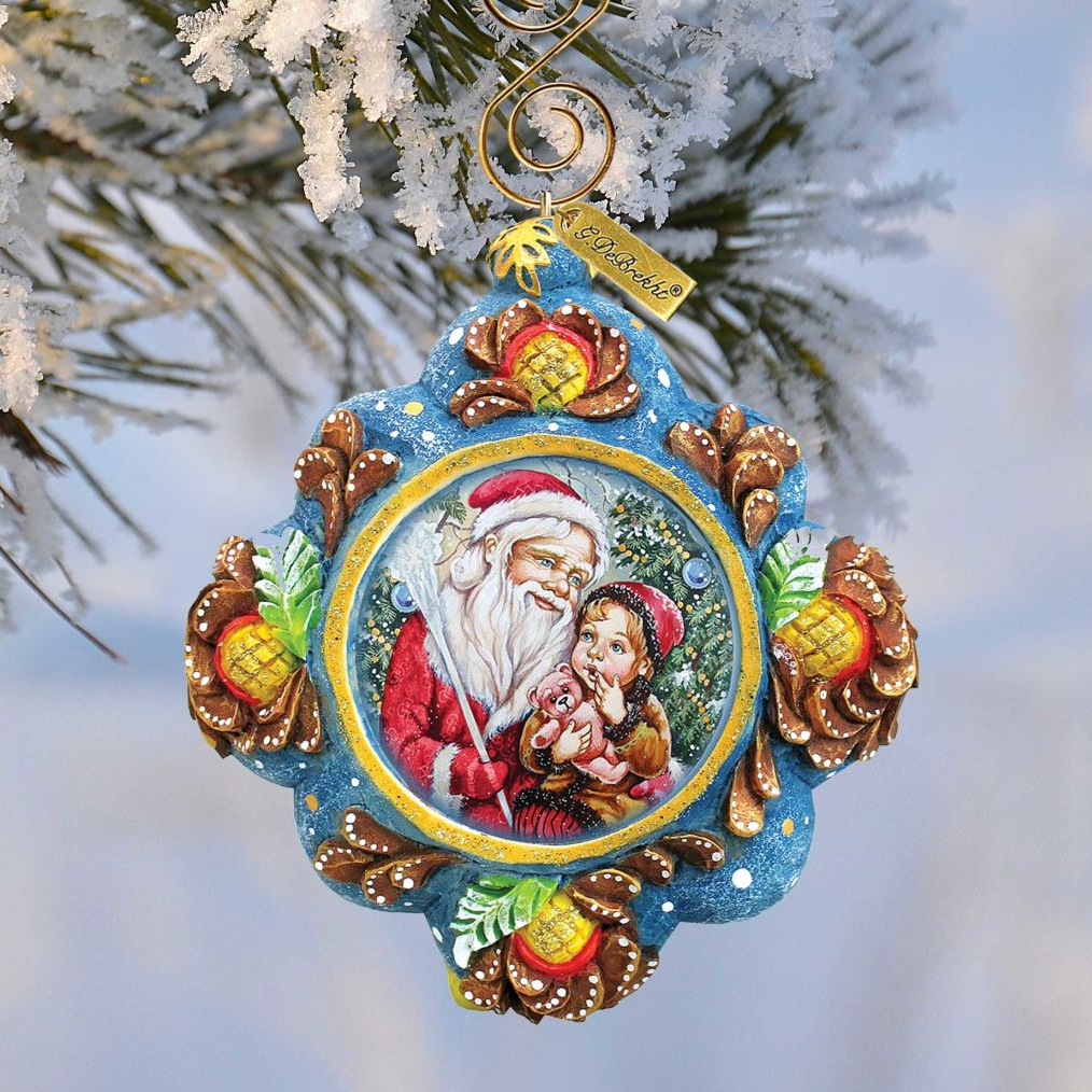 A decorative ornament featuring a painting of Santa Claus and a young girl, hanging on a tree branch with snow on the branches.