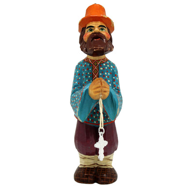 A wooden figurine of a bearded man wearing a hat and holding a cross.