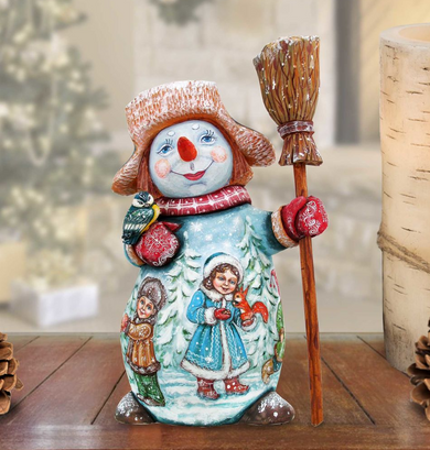 A colorful snowman figurine with a hat, scarf, and broom, holding a bird and a squirrel, is sitting on a wooden surface.