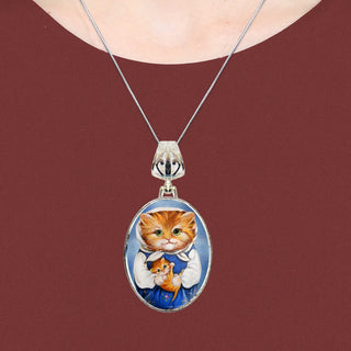A silver necklace with a pendant featuring a painting of a cat wearing a blue dress.