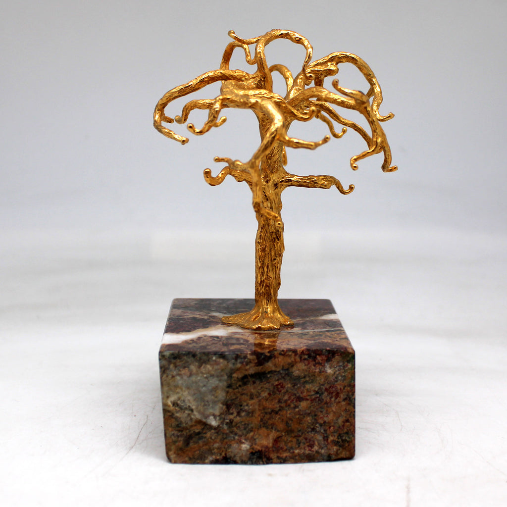 a gold sculpture of a tree on a marble block