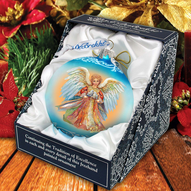 A blue and gold angel ornament in a box, surrounded by holiday decorations such as poinsettias and pine branches.