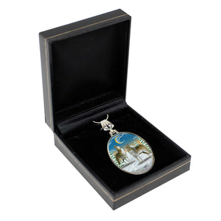 A silver pendant with a landscape scene featuring a wolf and a crescent moon, displayed in a black jewelry box.