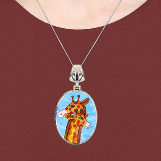 A necklace with a pendant featuring a painting of two giraffes.
