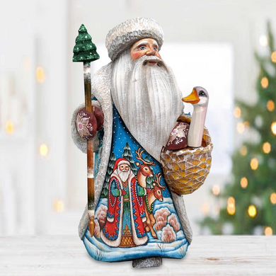 A colorful, handcrafted Santa Claus figurine holding a basket of reindeer and a bird, set against a blurred background of Christmas lights.
